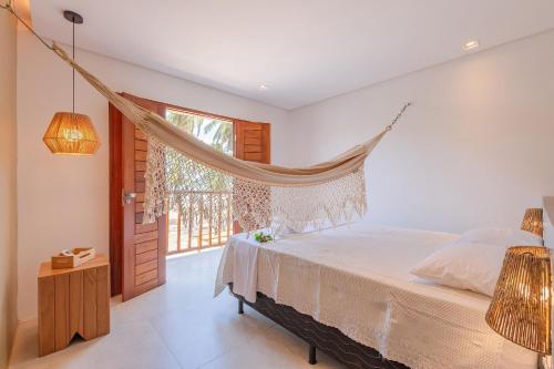a bedroom with a bed with a hammock in it at Casa LadoMar em Mundaú por Carpediem in Mundaú