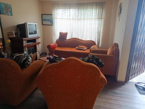uma sala de estar com dois sofás e uma televisão em Habitaciones en vivienda ubicada en urbanización privada em Cuenca