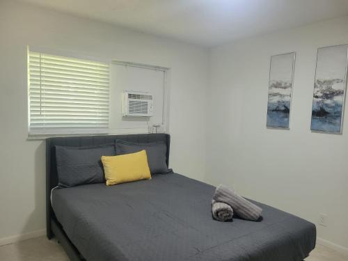a bedroom with a bed with a yellow pillow at Arpe 4plex in Fort Lauderdale