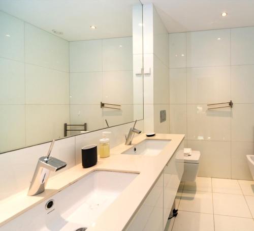 a white bathroom with two sinks and a toilet at Comfortable Apartment in Marquês de Pombal in Lisbon