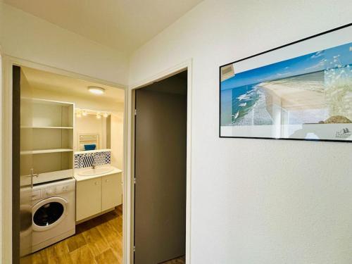 une cuisine avec un lave-linge et une photo sur le mur dans l'établissement L'encre bleue - 800 mètres de la plage, à Aytré