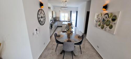 a room with a table and chairs and a clock on the wall at Seaside Serenity - Luxe Penthouse - near the beach by QuickTrips in Mellieħa