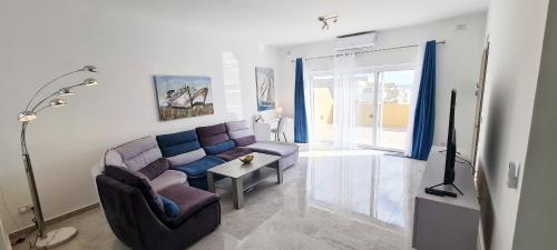 a living room with a couch and a table at Seaside Serenity - Luxe Penthouse - near the beach by QuickTrips in Mellieħa