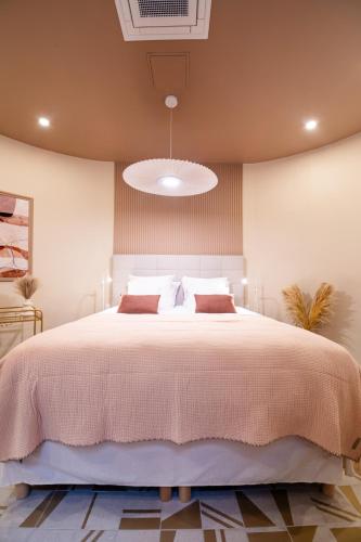 une chambre avec un grand lit avec une couverture rose dans l'établissement WS Louvre - Saint-Roch Luxe, à Paris