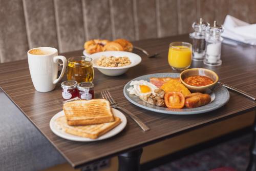 a wooden table with breakfast foods and drinks on it at Hilton Garden Inn Birmingham Airport Uk in Bickenhill