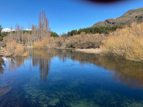 a river with blue water and trees in the background at Hometainer Río Cochrane 2 Cerro Tamango in Cochrane