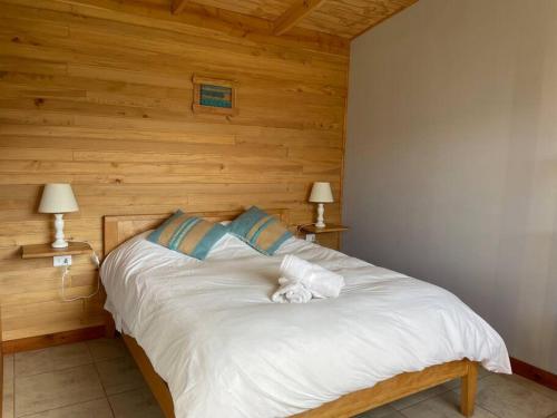a bedroom with a white bed with wooden walls at Hometainer Río Cochrane 2 in Cochrane