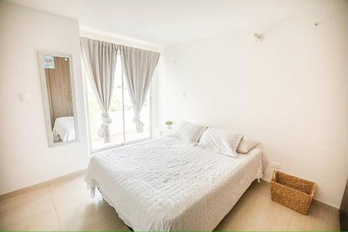 a white bedroom with a bed and a window at Espectacular apartamento en excelente sector in Yopal
