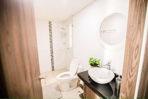 a bathroom with a toilet and a sink and a mirror at Espectacular apartamento en excelente sector in Yopal