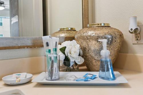 a bathroom counter with toothbrushes and a vase at Houston Med Center Modern Queen Suite with Spa Amenities, Pool and Free Parking in Houston