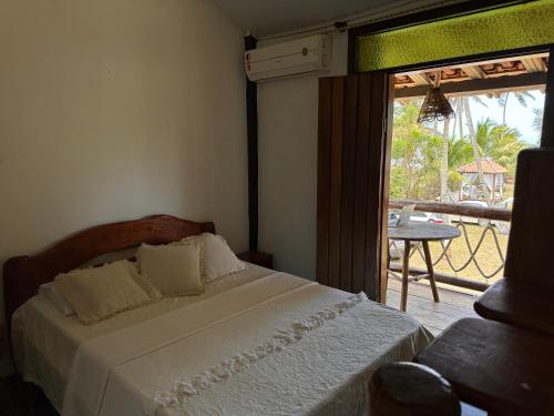 a bedroom with a bed and a view of a patio at Pousada Sargi&mar in Uruçuca