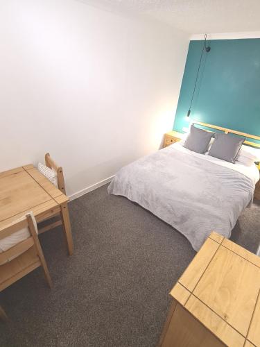 a bedroom with a bed with a blue headboard and a table at Five-star apartment in London