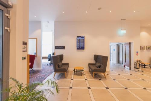 a waiting room at a hospital with chairs and a table at Hilton Garden Inn Birmingham Airport Uk in Bickenhill