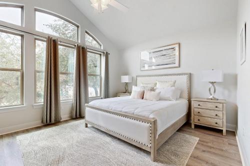 a white bedroom with a bed and windows at Point Venture Lookout in Lago Vista