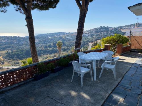 una mesa blanca y sillas en un patio con vistas en Villa Catalina - Vistamar, en Sant Cebrià de Vallalta