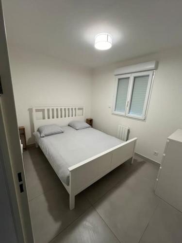 une chambre avec un lit blanc et une fenêtre dans l'établissement Bas de villa avec jardin, à Martigues