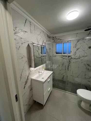 une salle de bain blanche avec un lavabo et une douche dans l'établissement Bas de villa avec jardin, à Martigues