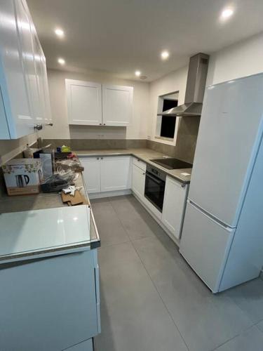 une cuisine avec des armoires blanches et un réfrigérateur blanc dans l'établissement Bas de villa avec jardin, à Martigues