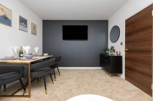 a dining room with a table and a television on a wall at Stunning modern space in Hove & free parking in Brighton & Hove