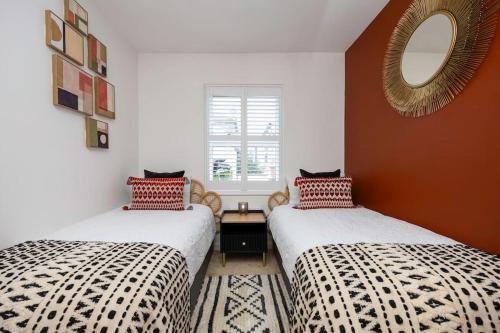 twee bedden in een kamer met een spiegel aan de muur bij Stunning modern space in Hove & free parking in Brighton & Hove