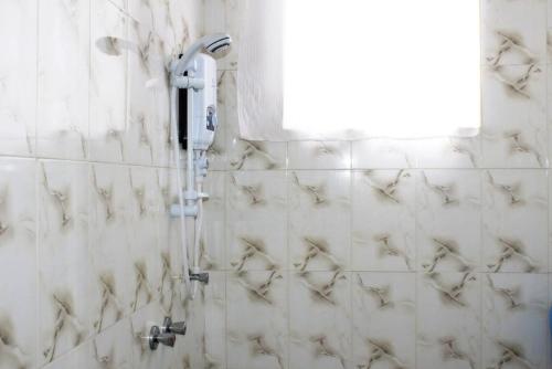 a shower in a white tiled bathroom at Afrodig Apartment in Arusha
