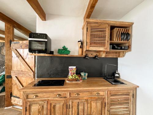 a kitchen with wooden cabinets and a microwave at Casita Mis Chinijos con Jacuzzi o Minipiscina in La Asomada