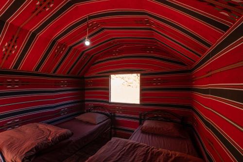 a red and black room with two beds in it at Wadi Rum Trail in Wadi Rum