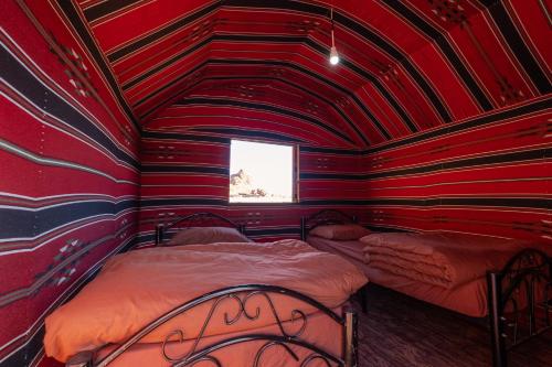 a red room with two beds in it with a window at Wadi Rum Trail in Wadi Rum