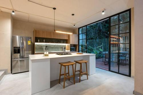 a kitchen with a white island with two bar stools at Casa Penta Top Notch Villa in Medellín