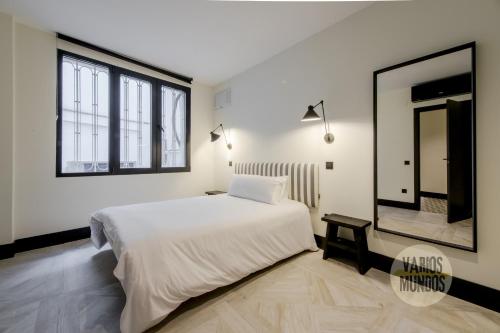 een slaapkamer met een groot wit bed en een spiegel bij Wonderful Apt para 7 en Preciados-Plaza del Carmen in Madrid