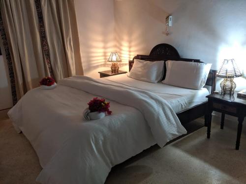 Un dormitorio con una gran cama blanca con flores. en Karibuni Villa - Malindi beach view property, en Malindi