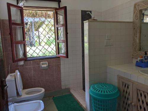 a bathroom with a toilet and a sink and a window at Karibuni Villa - Malindi beach view property in Malindi