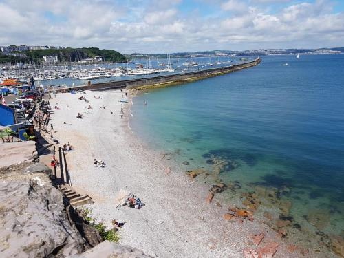 a beach with people and boats in a harbor at Stunning Penthouse views to harbour with parking. in Brixham
