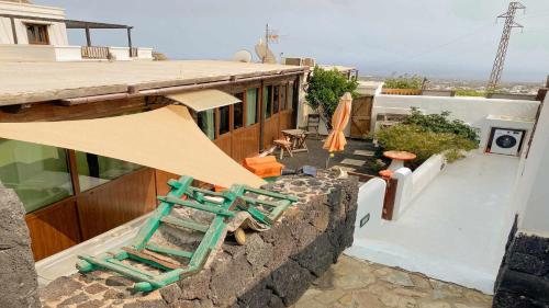 a balcony of a house with a green chair on a wall at Casita Mis Chinijos con Jacuzzi o Minipiscina in La Asomada