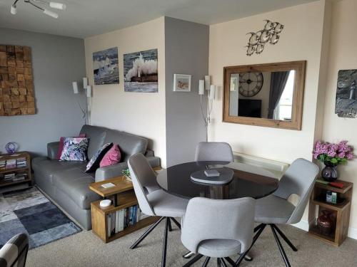a living room with a table and a couch at Stunning Penthouse views to harbour with parking. in Brixham