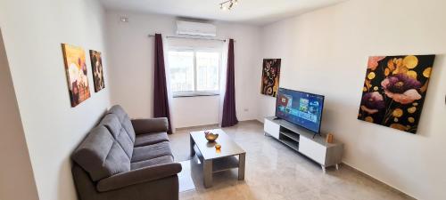 a living room with a couch and a television at Seaside Serenity 8 - few mins walk to the beach by QuickTrips in Mellieħa