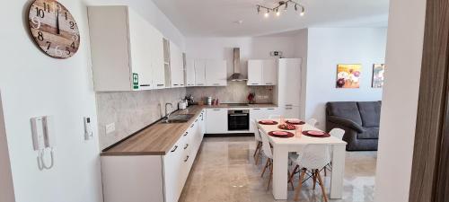 a kitchen with white cabinets and a table with chairs at Seaside Serenity 8 - few mins walk to the beach by QuickTrips in Mellieħa