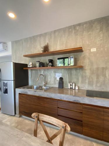 a kitchen with a sink and a stainless steel refrigerator at Panacea Condo Tulum in Tulum