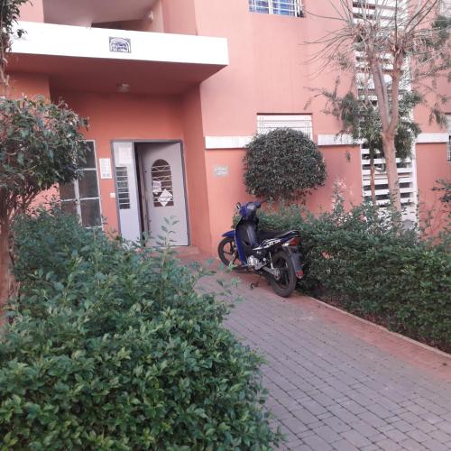 een motorfiets geparkeerd voor een roze gebouw bij ديار المنصور بني ملال المغرب in Beni Mellal