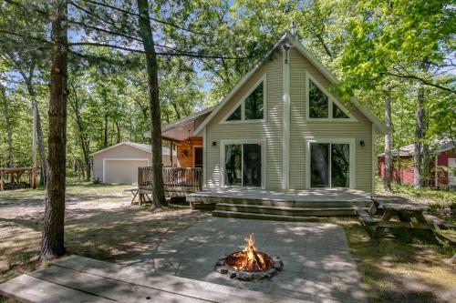 a house with a fire pit in front of it at A-Frame Cabin with a Game Room Across From Big Star Lake Boat Launch in Baldwin