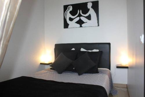 a bedroom with a bed with black pillows and two lights at Apartamento Matur in Santa Cruz