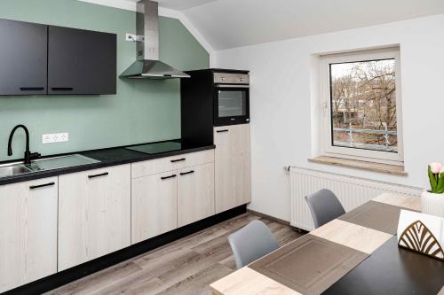 une cuisine avec des placards blancs, une table et une fenêtre dans l'établissement nice2be Apartments, à Augsbourg