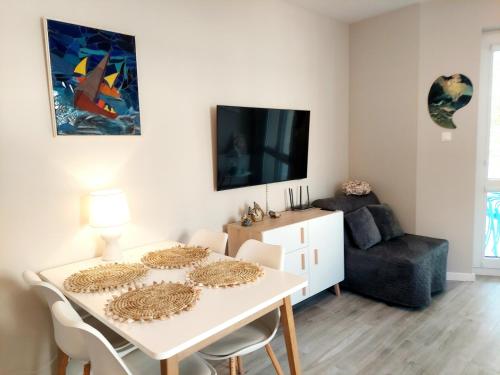 ein Wohnzimmer mit einem weißen Tisch und einem TV in der Unterkunft Apartament Morze Sztuki II, Jantar in Jantar