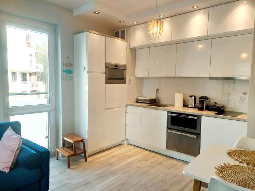 eine Küche mit weißen Schränken und einer blauen Couch in der Unterkunft Apartament Morze Sztuki II, Jantar in Jantar