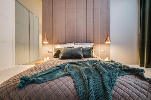 a bedroom with a large bed with a blanket at Apartamenty Tespis - Francuska Atal Park PREMIUM in Katowice