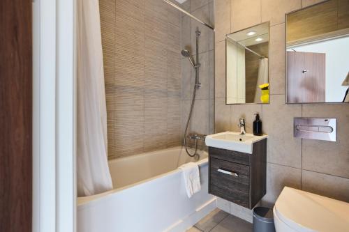 a bathroom with a tub and a sink and a toilet at The Harlesden Place - Modern 3BDR Flat with Balcony in London