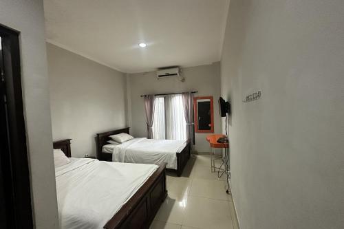 a hotel room with two beds and a television at Hotel Warta Dua in Denpasar
