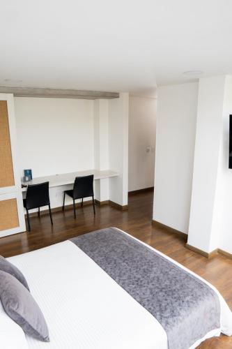 a bedroom with a white bed and a desk at Hotel Piedras De Maní in Manizales