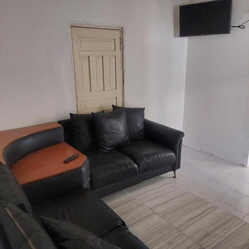 Apartamento céntrico cómodo في تشيواوا: أريكة جلدية سوداء في غرفة معيشة مع باب