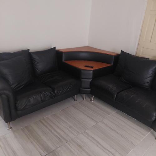 Apartamento céntrico cómodo في تشيواوا: أريكة جلدية سوداء مع طاولة في الغرفة